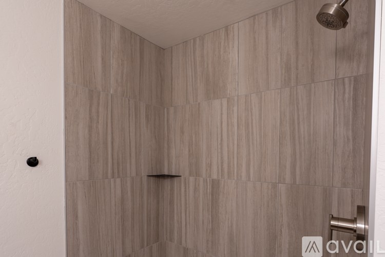 A shower area with a wall of tiles and a shower head.