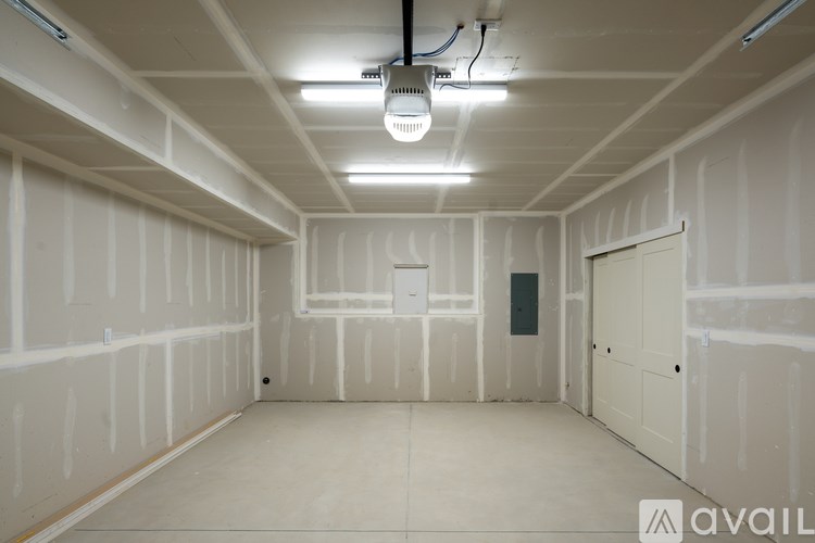 A spacious room with drywall on the walls and a door on the right.