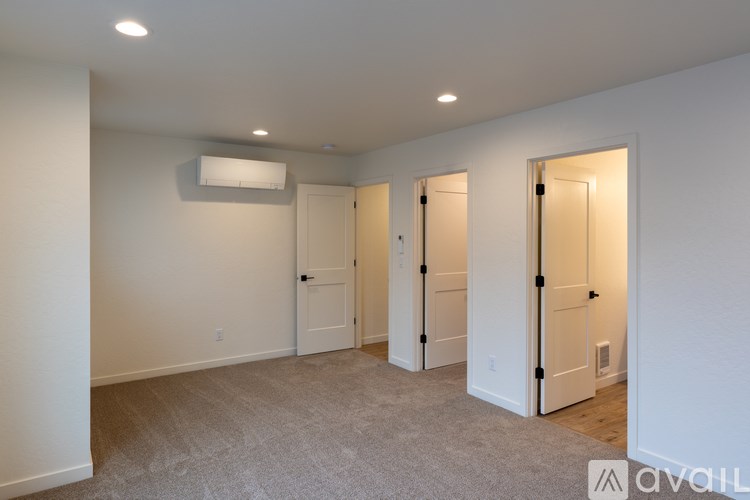 A room with a carpeted floor and a white ceiling with three doors.