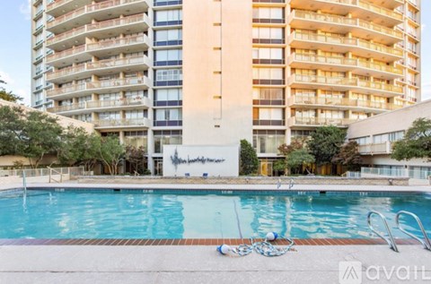 A large swimming pool in front of a tall apartment building.