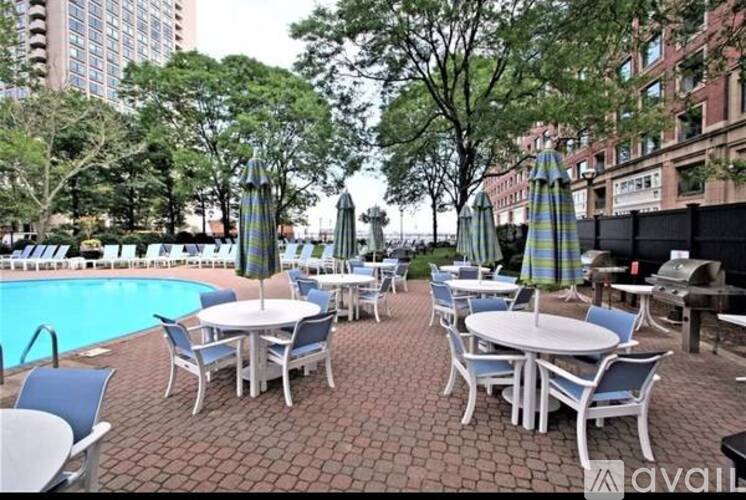 A poolside area with tables and chairs and umbrellas.