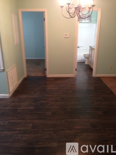 A hallway with wood floors and a chandelier.