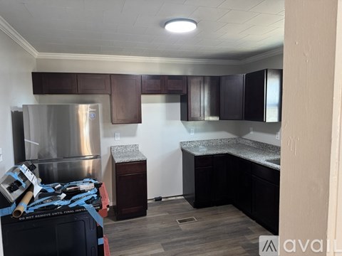 A kitchen with dark wood cabinets and a stainless steel refrigerator.