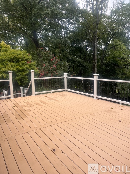 A wooden deck with a white railing and trees in the background.