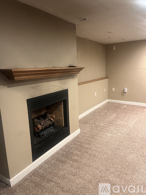 A living room with a fireplace and carpeted floor.