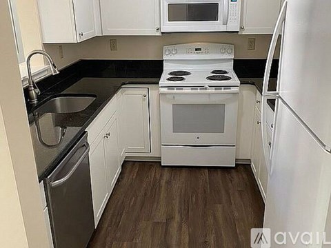 A kitchen with white appliances and wooden floors.