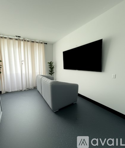 A living room with a grey couch and a flat screen TV mounted on the wall.