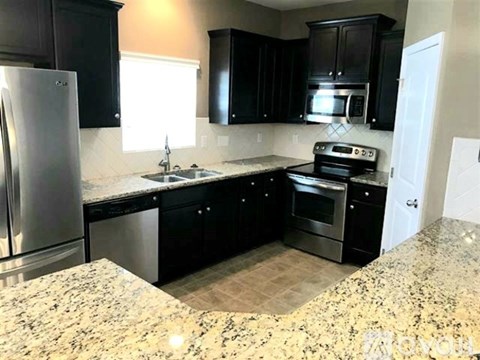 A kitchen with black cabinets and granite countertops.