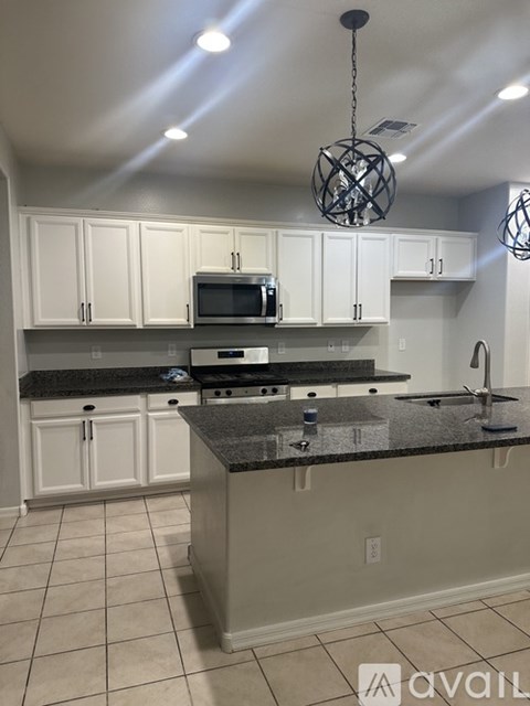 A kitchen with white cabinets and a granite countertop.