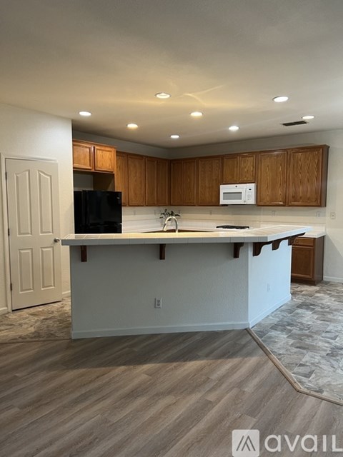 A kitchen with wooden cabinets and a black fridge.