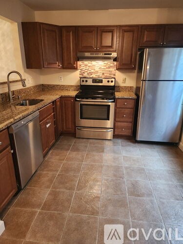 A kitchen with brown cabinets and a tile floor.