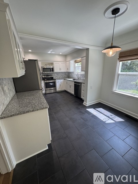 A kitchen with black tiles on the floor and white cabinets.
