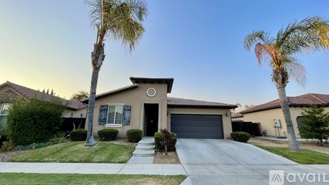 A house with a driveway and two palm trees in front.