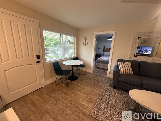 A living room with a grey couch, a round table, and a white door.