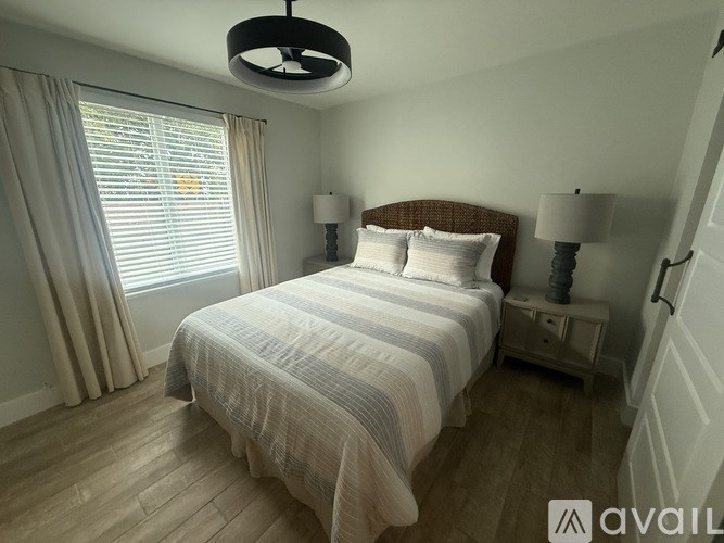 A bedroom with a large bed and a window with curtains.