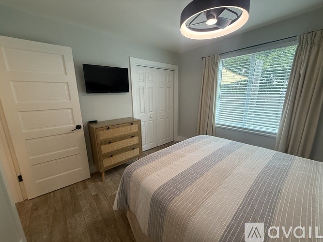 A bedroom with a bed, a dresser, and a television.