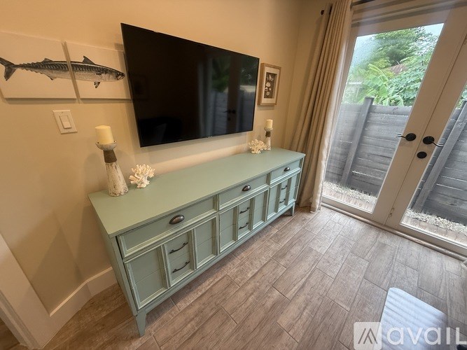 A green cabinet with a flat screen TV mounted above it.