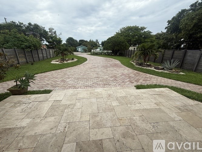 A driveway with a brick pattern leads to a house.