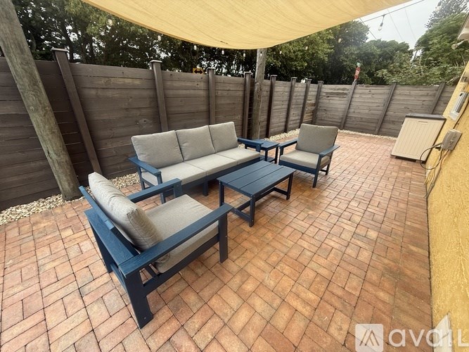 A patio with a couch and two chairs under a canopy.