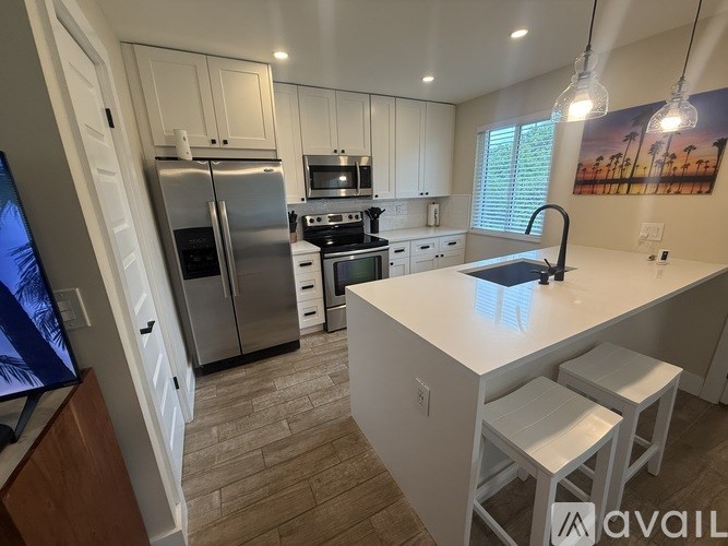 A kitchen with white cabinets and a stainless steel refrigerator.