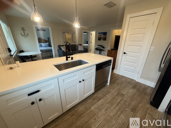 A kitchen with white cabinets and a wooden floor.