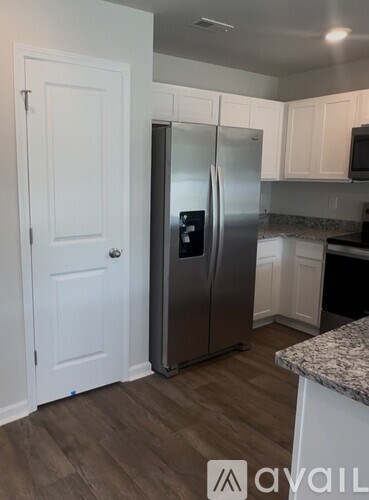A kitchen with a stainless steel refrigerator and white cabinets.