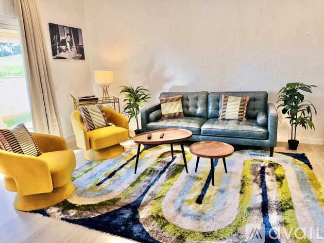 A living room with a blue couch, yellow chairs, and a rug.