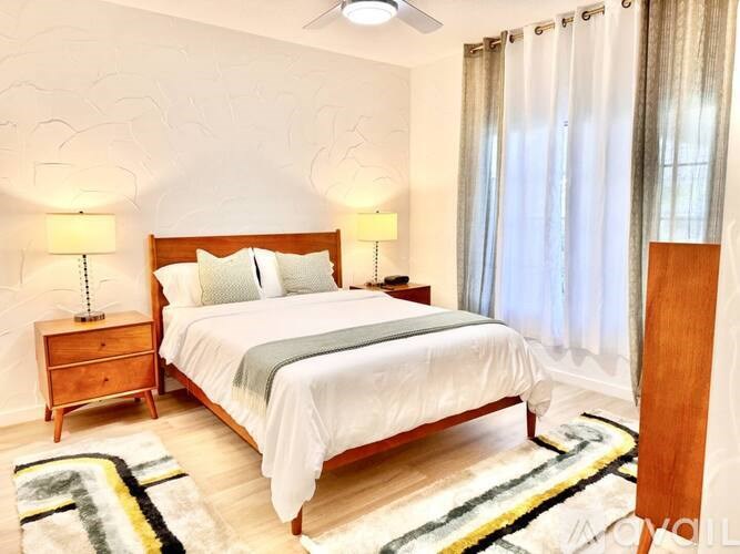 A bedroom with a bed, nightstands, and a rug.