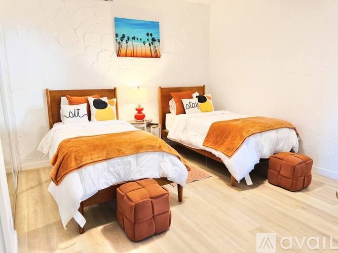 Two twin beds with white bedding and orange throw blankets in a room.