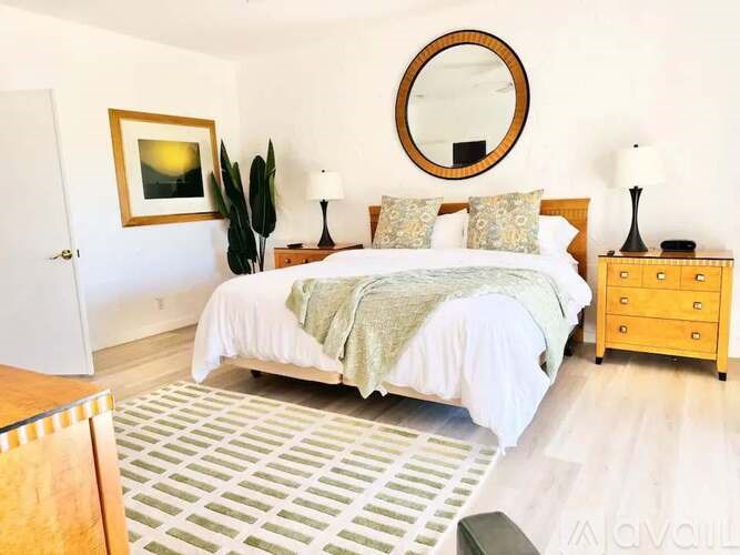 A bedroom with a bed, nightstand, and a painting on the wall.