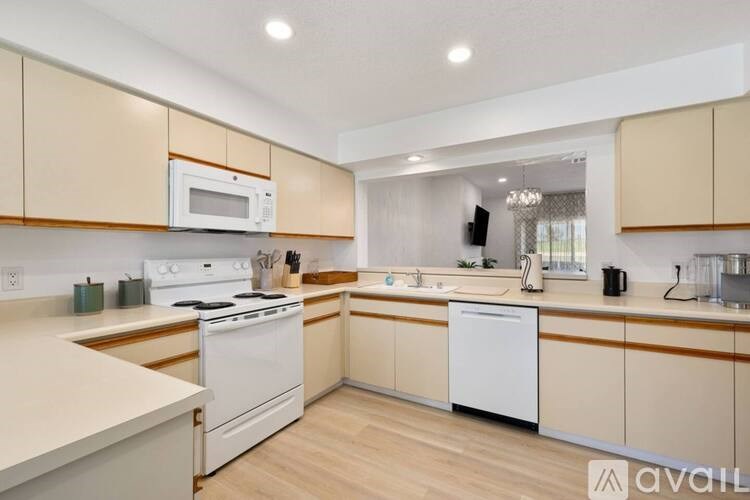 A kitchen with white appliances and wooden cabinets.