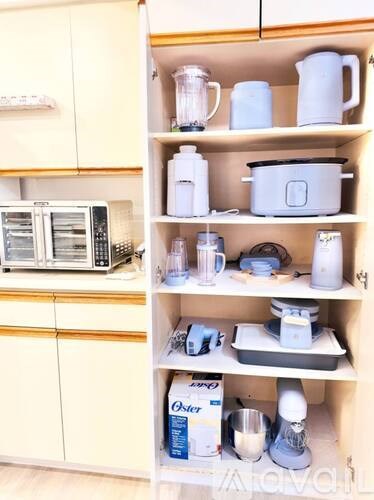 A kitchen with a microwave, oven, and various kitchen appliances on the shelves.