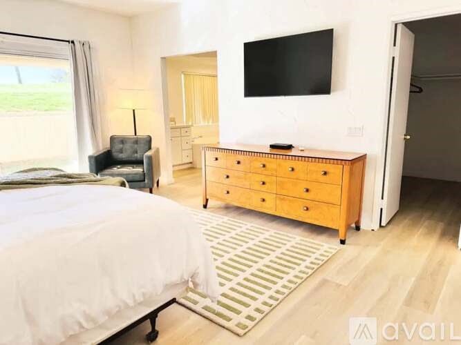 A bedroom with a bed, a dresser, and a television.