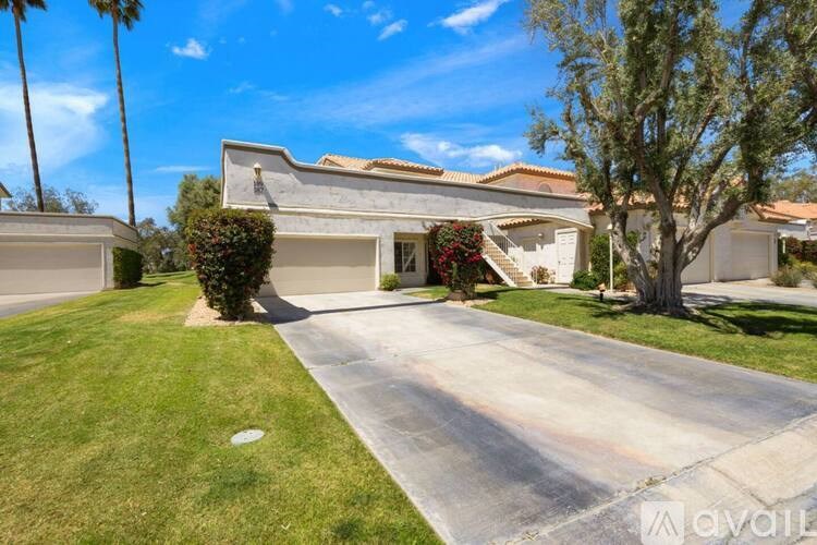 A house with a driveway and a tree in front.
