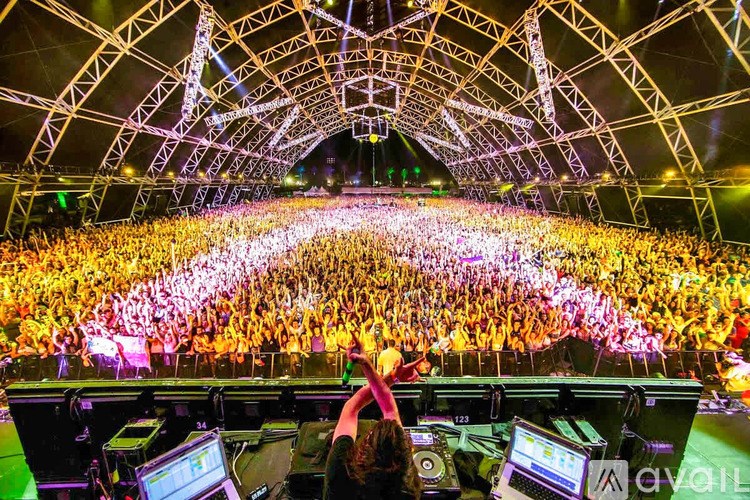 A DJ mixes music in front of a large crowd at a concert.