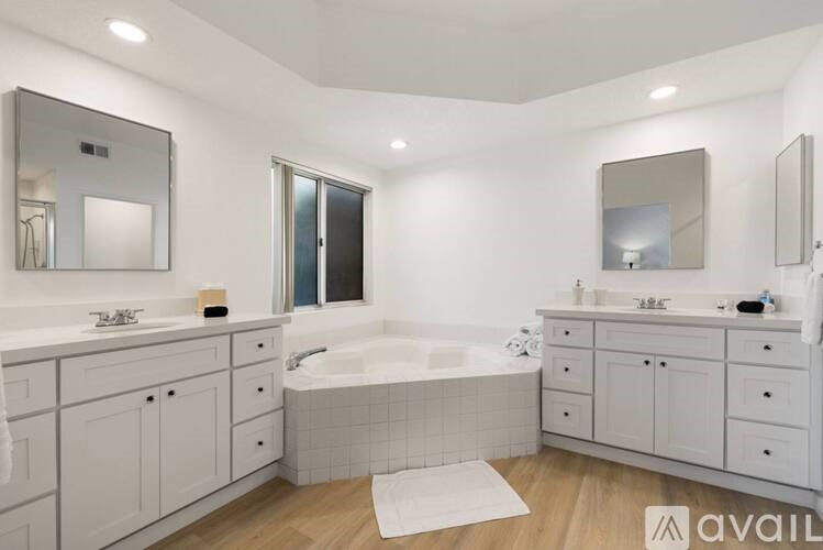 A bathroom with a white color scheme and a large tub.