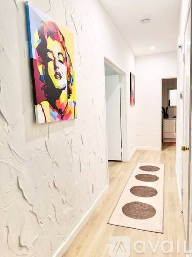 A hallway with a painting on the wall and a rug on the floor.