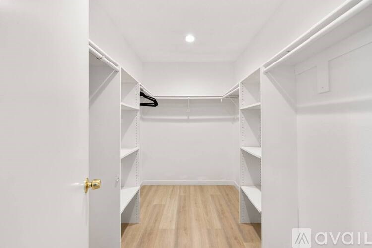 A white hallway with a wooden floor and a white door.