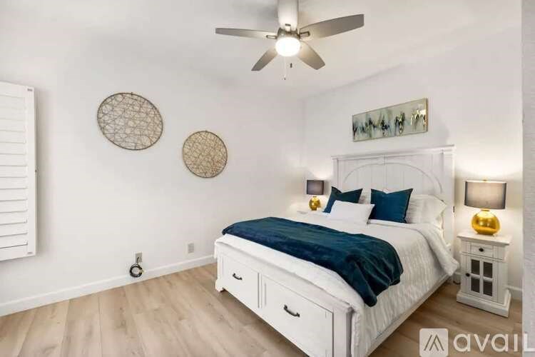 A bedroom with a white bed and a ceiling fan.