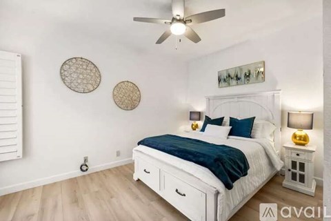 A bedroom with a white bed and a ceiling fan.