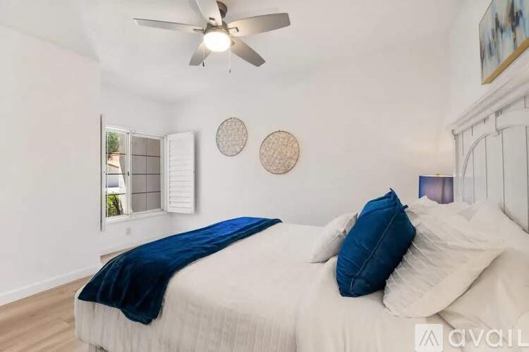 A bedroom with a bed, a ceiling fan, and a window with blinds.