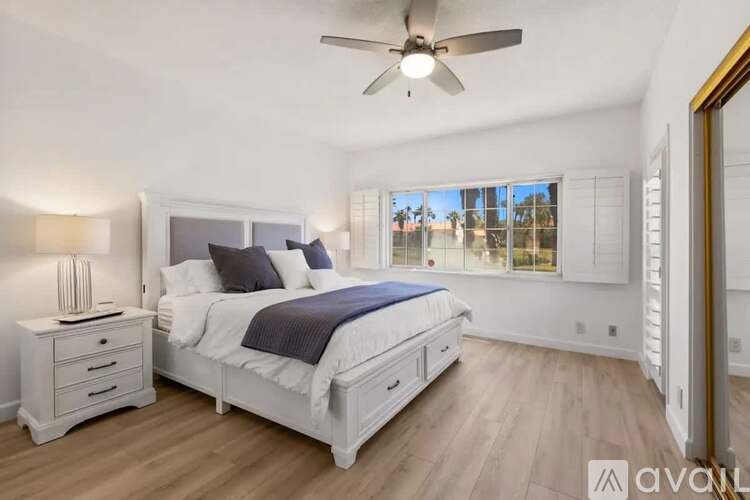A bedroom with a bed, nightstand, and a ceiling fan.