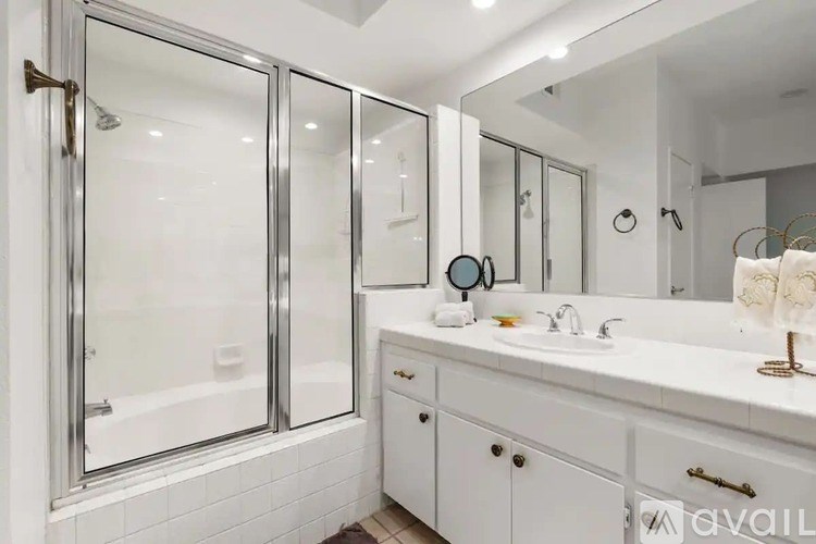 A bathroom with a white sink, mirror, and a glass shower door.
