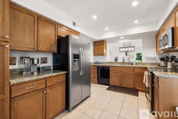 A kitchen with wooden cabinets and a black fridge.
