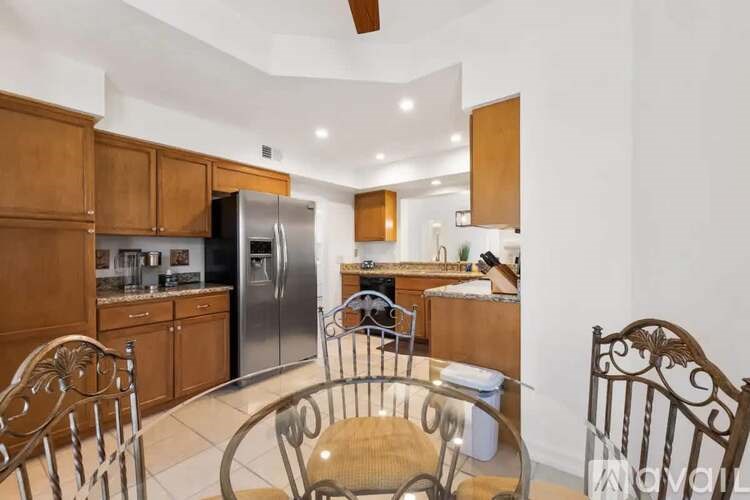 A kitchen with wooden cabinets and a glass table with chairs.