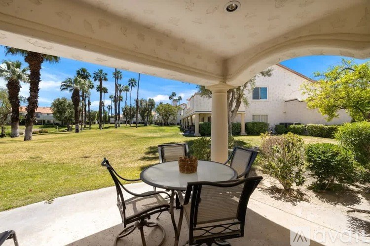 A patio with a table and chairs under a roof.