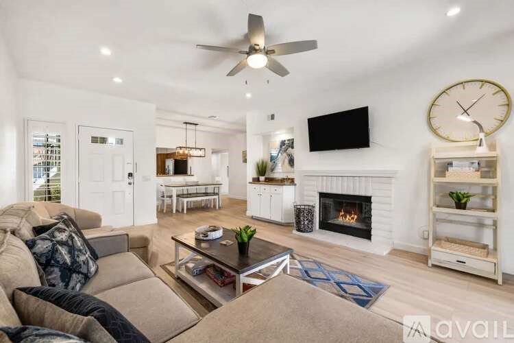 A living room with a fireplace, a couch, a coffee table, and a TV mounted on the wall.