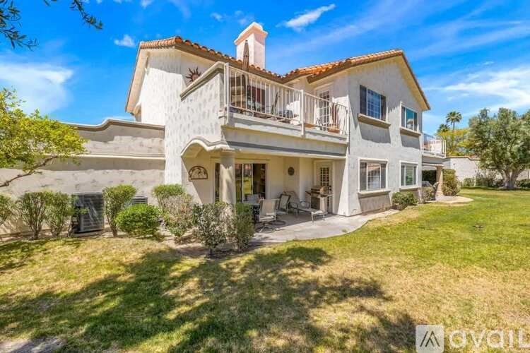 A large two-story house with a balcony and a red tile roof.