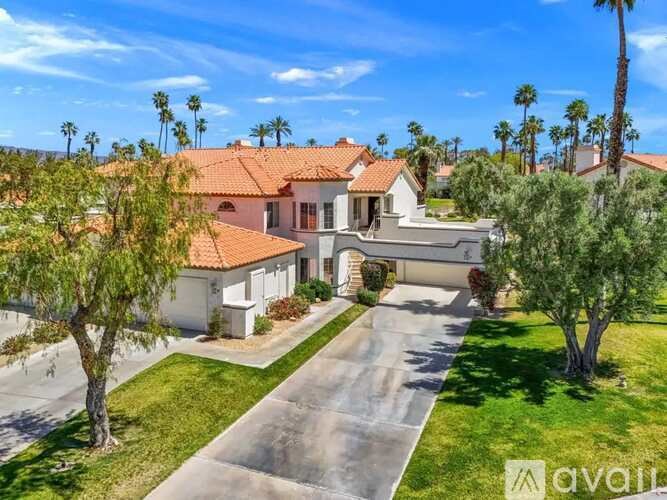 A house with a driveway and palm trees in the background.