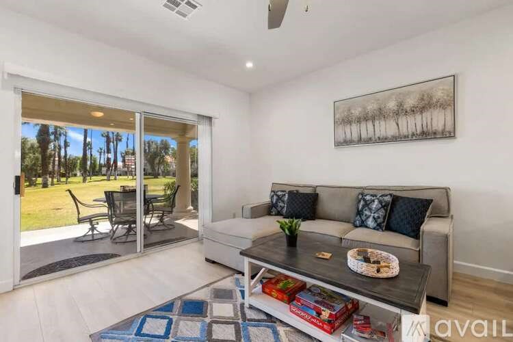 A living room with a grey couch and a painting on the wall.